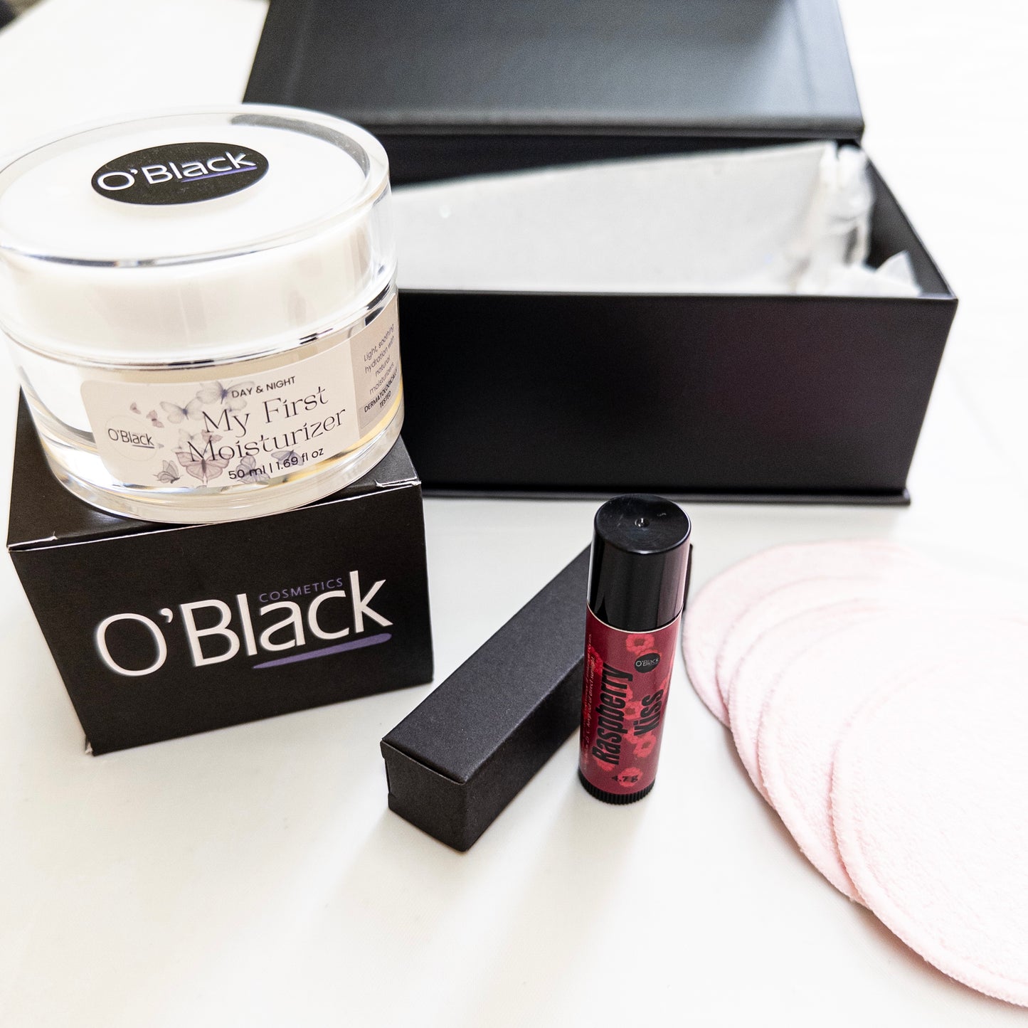 O'Black skincare products including a moisturizer, lip balm, and make up remover pads