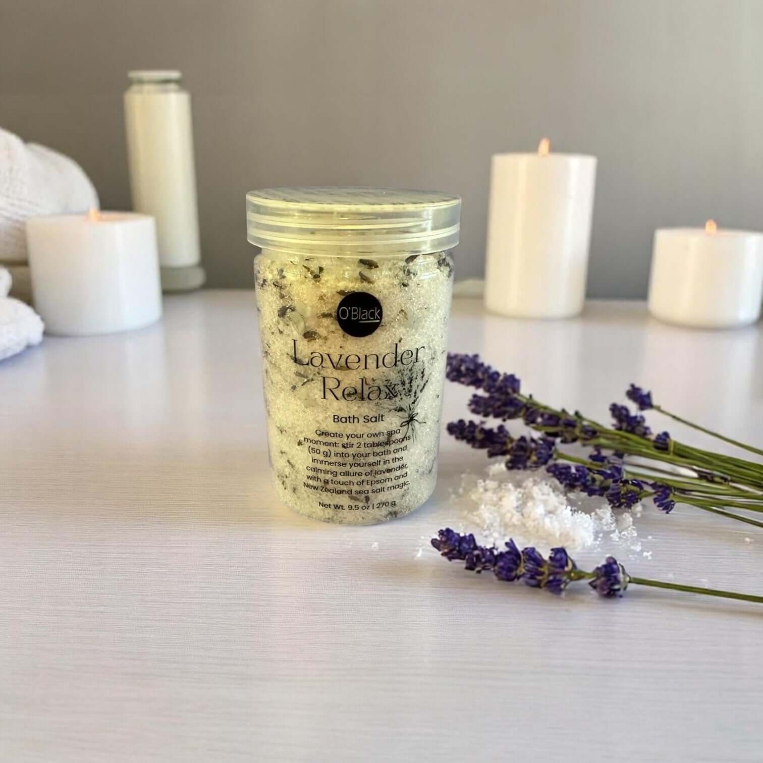 Jar of lavender bath salt with candles and lavender flowers on a table