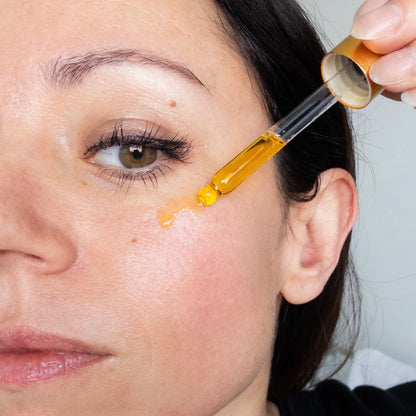 Woman applying a dropper of oil to her face