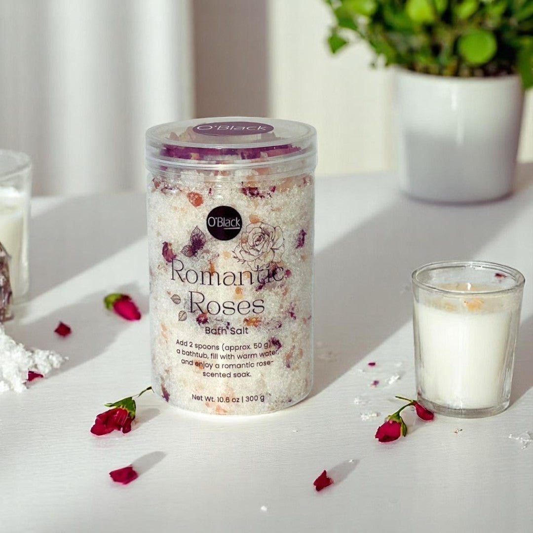 Bath salt container labeled 'Romantic Roses' on a white surface with a candle and rose petals.