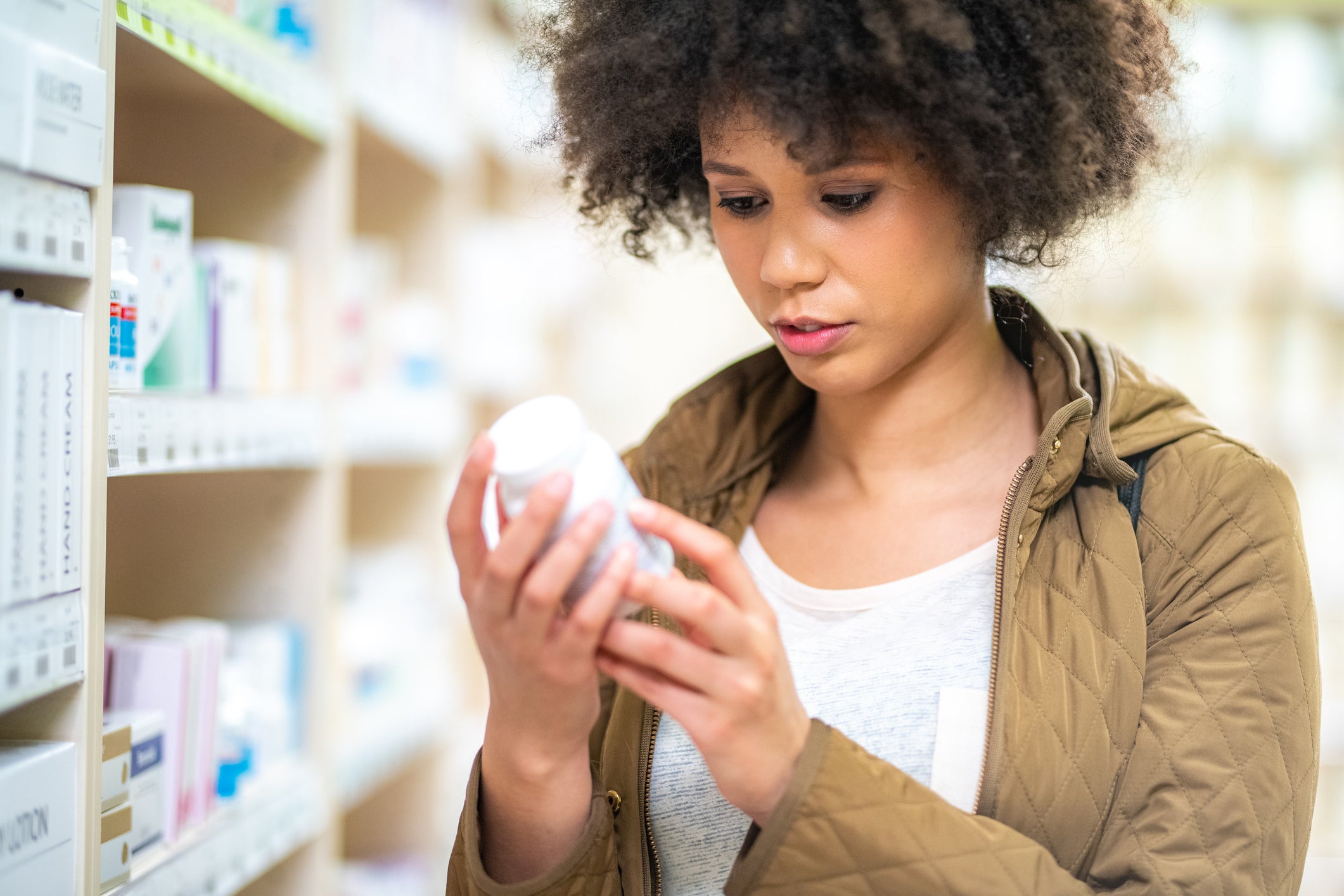 Woman in a pharmacy holding a bottle of medication
