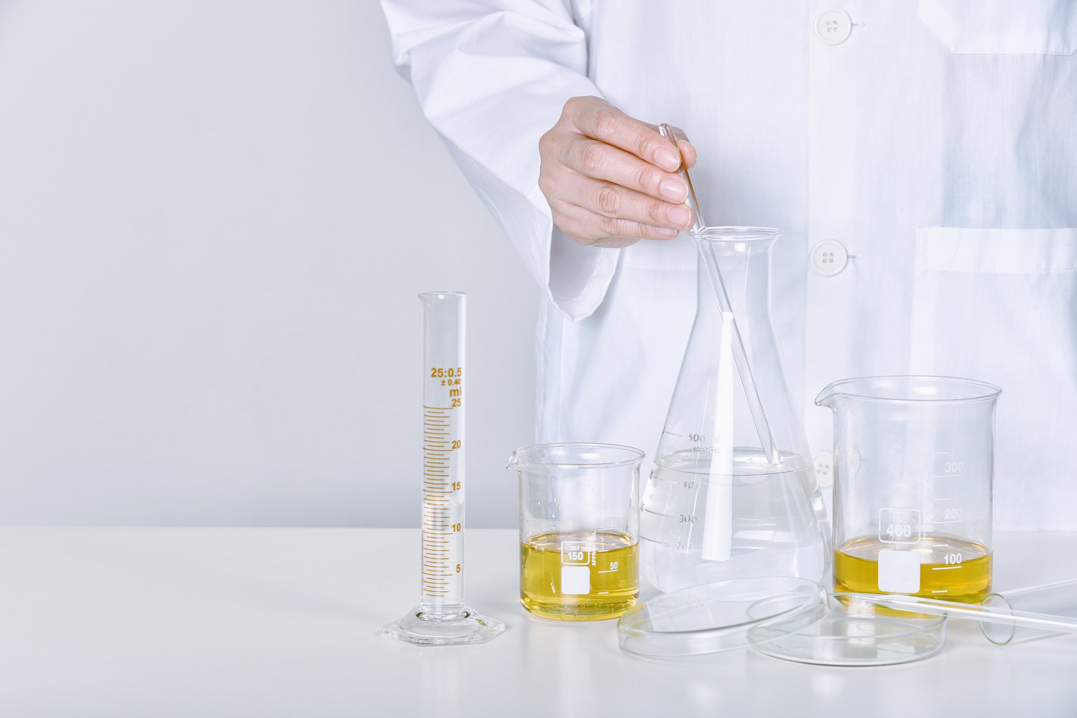 Laboratory equipment with some oils in beakers and chemist at the back